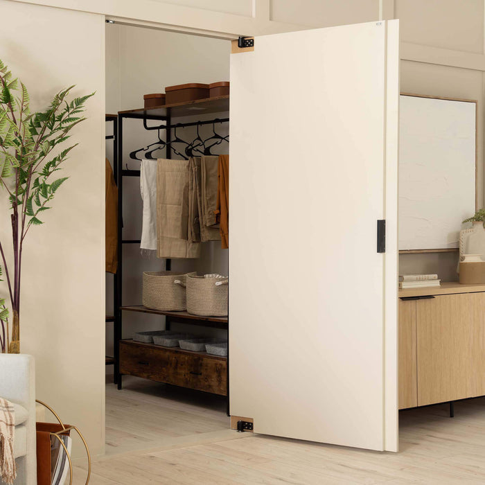 Murphy Door® white sliding hidden closet door, partially open revealing clothing rack, storage bins, and wooden shelving in a minimalist interior.